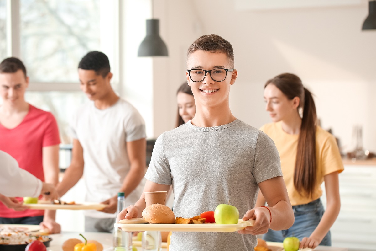 Schüler trägt gesundes Essen auf einem Tablett